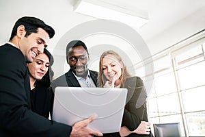 African businessman and Caucasian businesswomen intend to listen to colleagues and looking on a laptop at an internal business