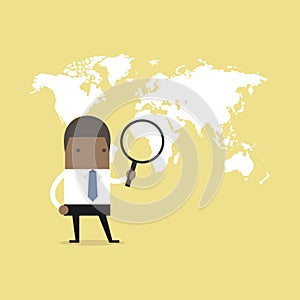 African businessman holding magnifying glass finding over world map.