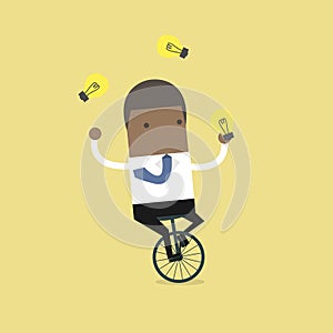 African businessman juggling money bag while cycling.African businessman juggling light bulb while cycling.