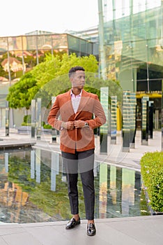 African businessman outdoors in city thinking full length shot