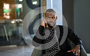 African businessman talking on his cellphone in an office lobby. Dressed on traditional clothing