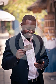 African businessman using a credit card payment shopping online on his Smart Phone