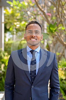 African businessman wearing suit and smiling outdoors vertical shot