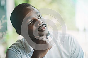 African businessman in white shirt looking out the window, thinking about workplace business problems.Black man sits and thinks