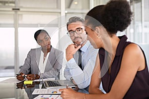 African businesswoman explaining graphs to her pensive boss