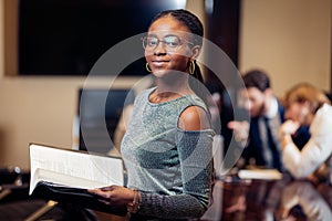 African businesswoman look at camera in boardroom with colleagues in background