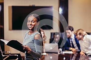 African businesswoman look at camera in boardroom with colleagues in background