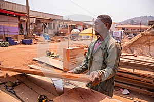 An african carpenter during work takes a board of wood to be cut