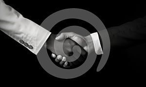 African and a caucasian man shaking hands over black background