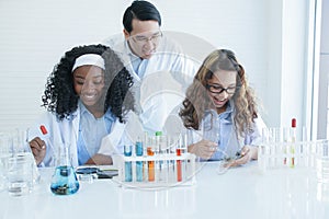 African and Caucasian scientist girl students are doing science experiments in laboratory with Asian teacher man