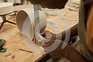 African ceramist measuring a pot at a bench in a workshop photo
