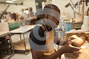 African ceramist working on a clay bowl at a studio bench photo