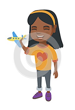African cheerful girl playing with a toy airplane