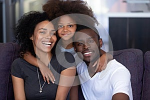 African child daughter embracing young loving black parents, portrait photo