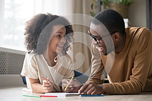 African child girl drawing with pencils having fun with dad