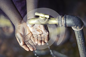 African Child with Hands Cupped under Water Tap in Bamako