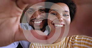 African couple faces looking through joined fingers making heart shape