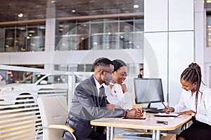 African couple getting car key from dealer in showroom and signing contract