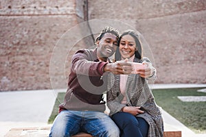 African couple having fun doing selfie outdoor in the city - Focus on woman face