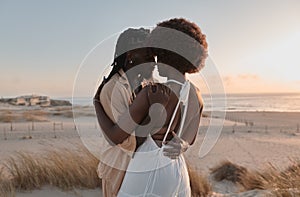 African couple hugging on beach at sunset