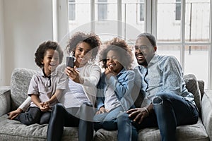 African couple with little kids making selfie seated on couch