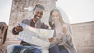 African couple looking city map during vacation tour - Happy young people having fun in down town center - Travel, love and