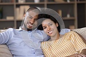 African couple in love relaxing on sofa look at camera