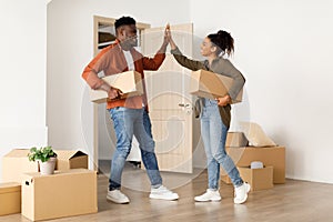 African Couple Moving New House Holding Boxes Giving High-Five Indoors