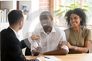 Realtor giving keys to new house to african married couple