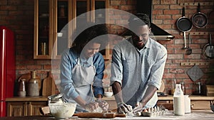 African couple standing in kitchen kneading dough cooking together