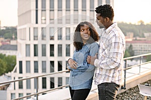 African couple woman and man hugging on rooftop of modern building.