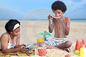 African curly hair boy and girl sibling on beach. Happy smiling two kid friend playing together on sand beach. Joyful children