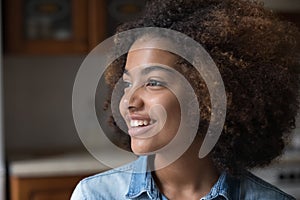 African curly-haired teenage girl smiling staring into distance