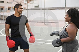 African curvy woman and personal trainer doing boxing workout session outdoor - Focus on girl face