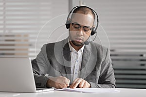 African customer support agent wear headset write notes make videocall photo
