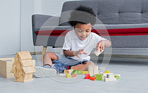 African cute boy playing toys, laughing and sitting on the floor in living room at home. Education and Lifestyle Concept