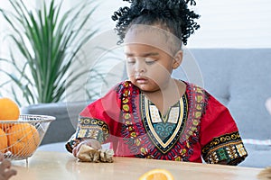 African cute kid girl cleaning table from fresh oranges juice spilled all over the table at home. Adorable child using tissue