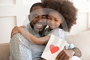 African dad embracing daughter holding greeting card on fathers day photo