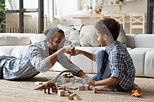 African dad play wooden cubes with little son at home