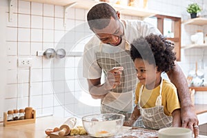 African Dad playing with son while baking cake