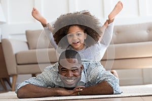 African daughter performs yoga boat pose on father back