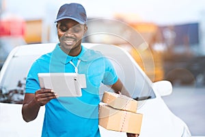 African delivery worker wearing a hat and uniform views delivery information using a tablet