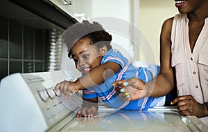 African descent kid helping mom doing the laundry