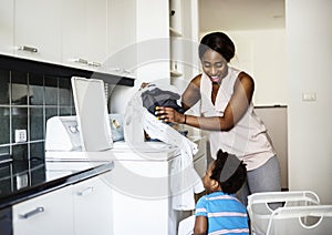 African descent kid helping mom doing the laundry