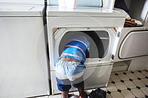 African descent kid helping mom doing the laundry