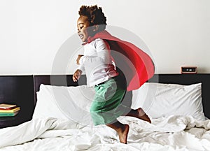 African descent kid jumping on the bed with robe