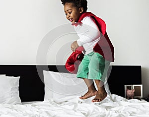 African descent kid jumping on the bed with robe