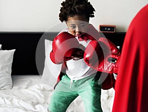 African descent kid wearing robe doing boxing with dad on the be