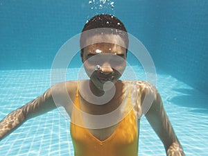 African descent woman smiling underwater in swimming pool