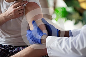 African doctor doing injection of vaccine to male patient